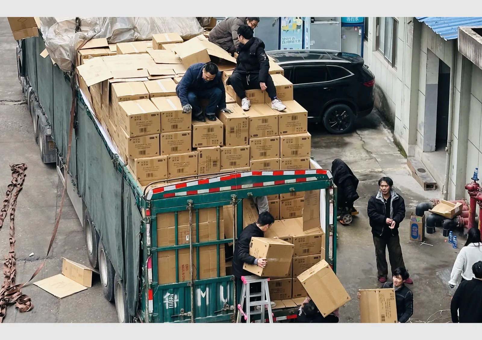 Workers loading export container with collapsible stool cartons for wholesale shipment from Yiwu China factory